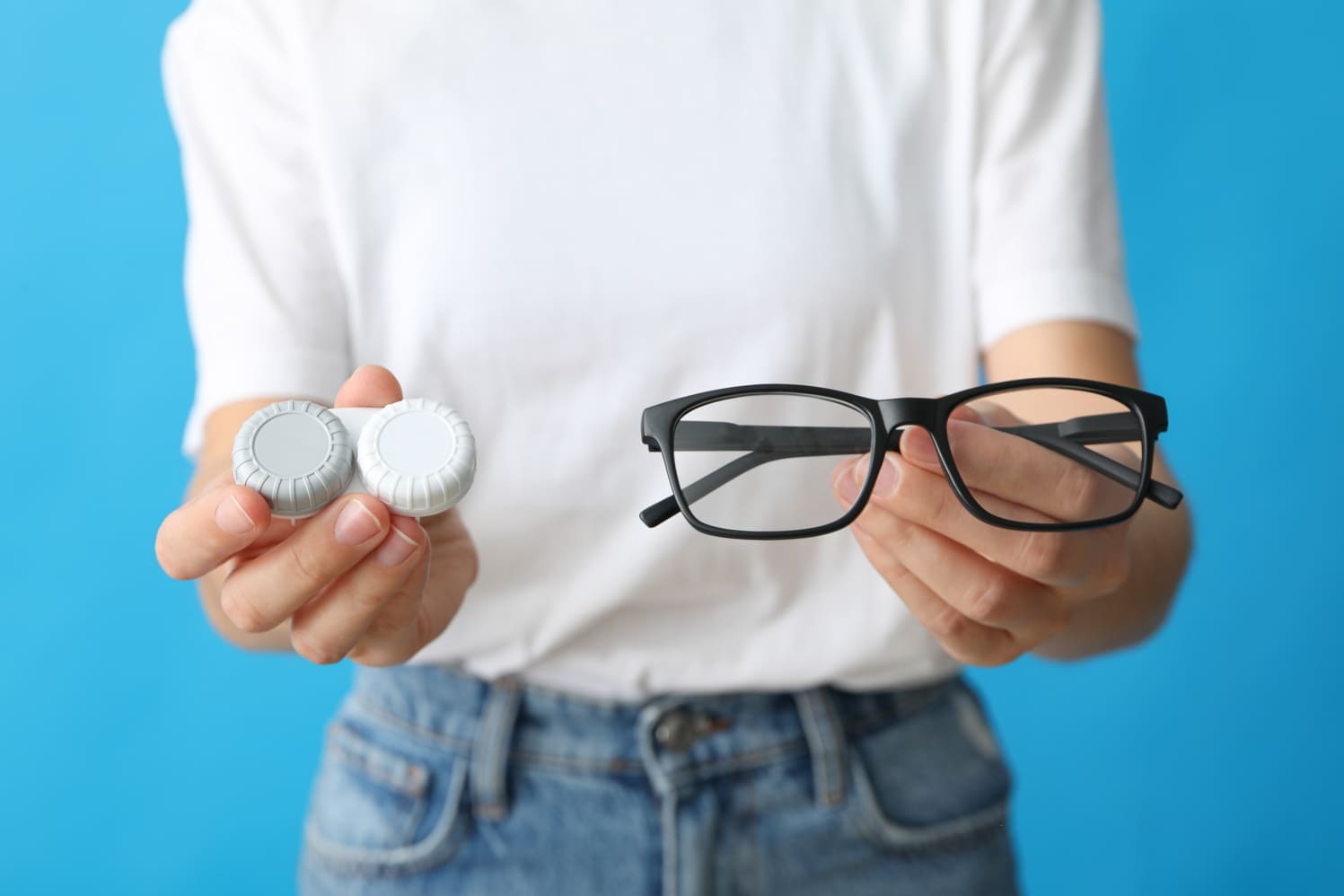 Persona sosteniendo unas gafas y un estuche de lentes de contacto